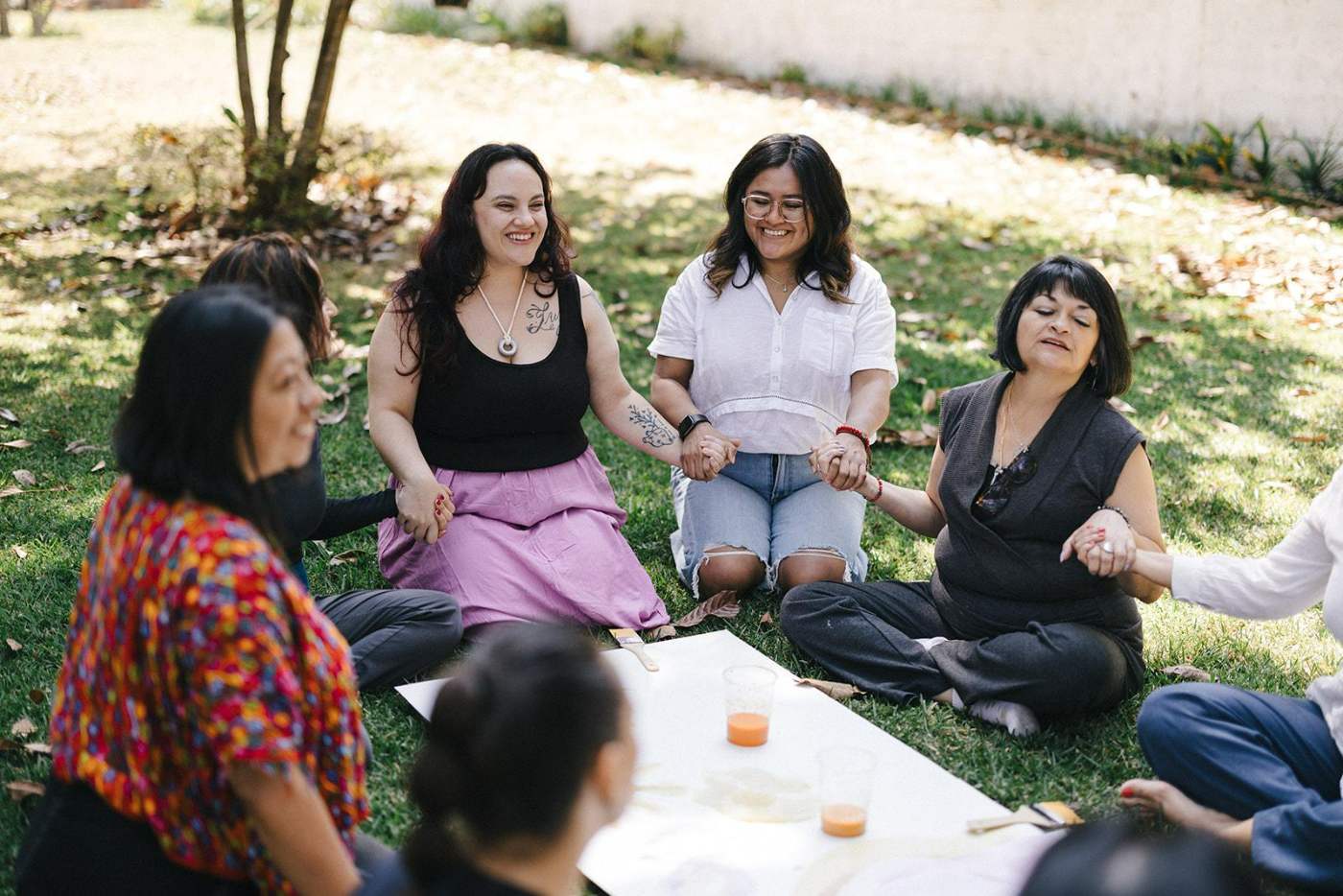 Círculo de mujeres tomadas de las manos en un jardín